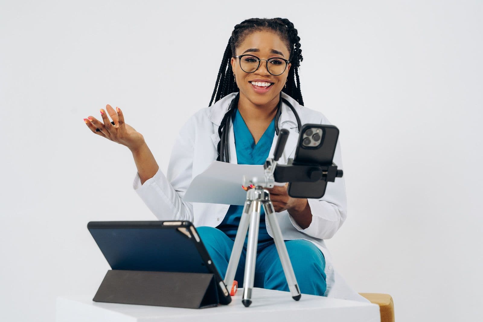A physiotherapist smiling mid-consultation, her tablet set up for the call