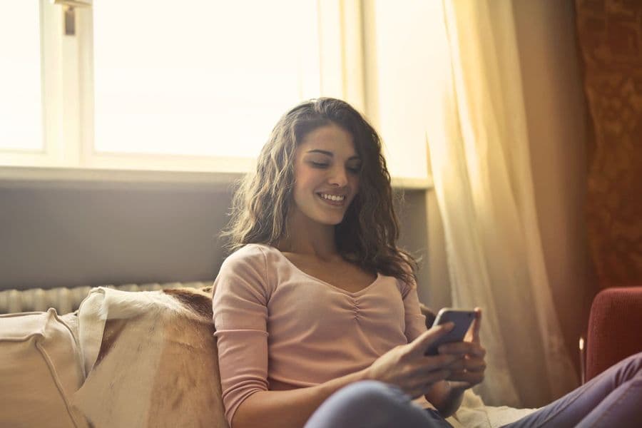 A patient smiling as she books her session on her phone